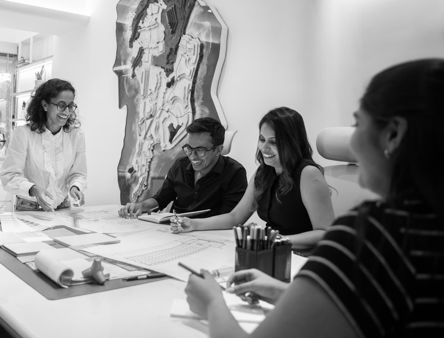 The team reviewing drawings around the studio table